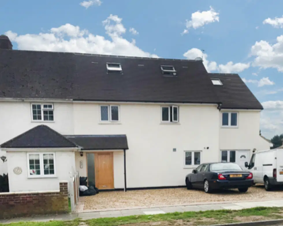 White semi-detached house with parked cars outside.
