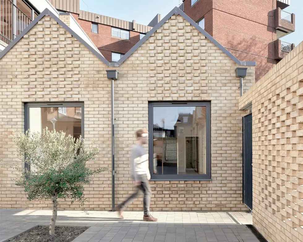 Person walking past a modern brick building.